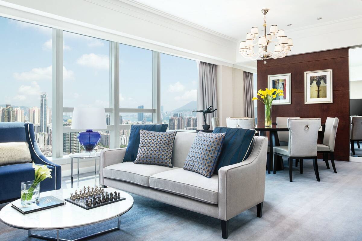 A modern living room with a sofa, armchair, and coffee table, featuring a chess set and a vase of flowers.