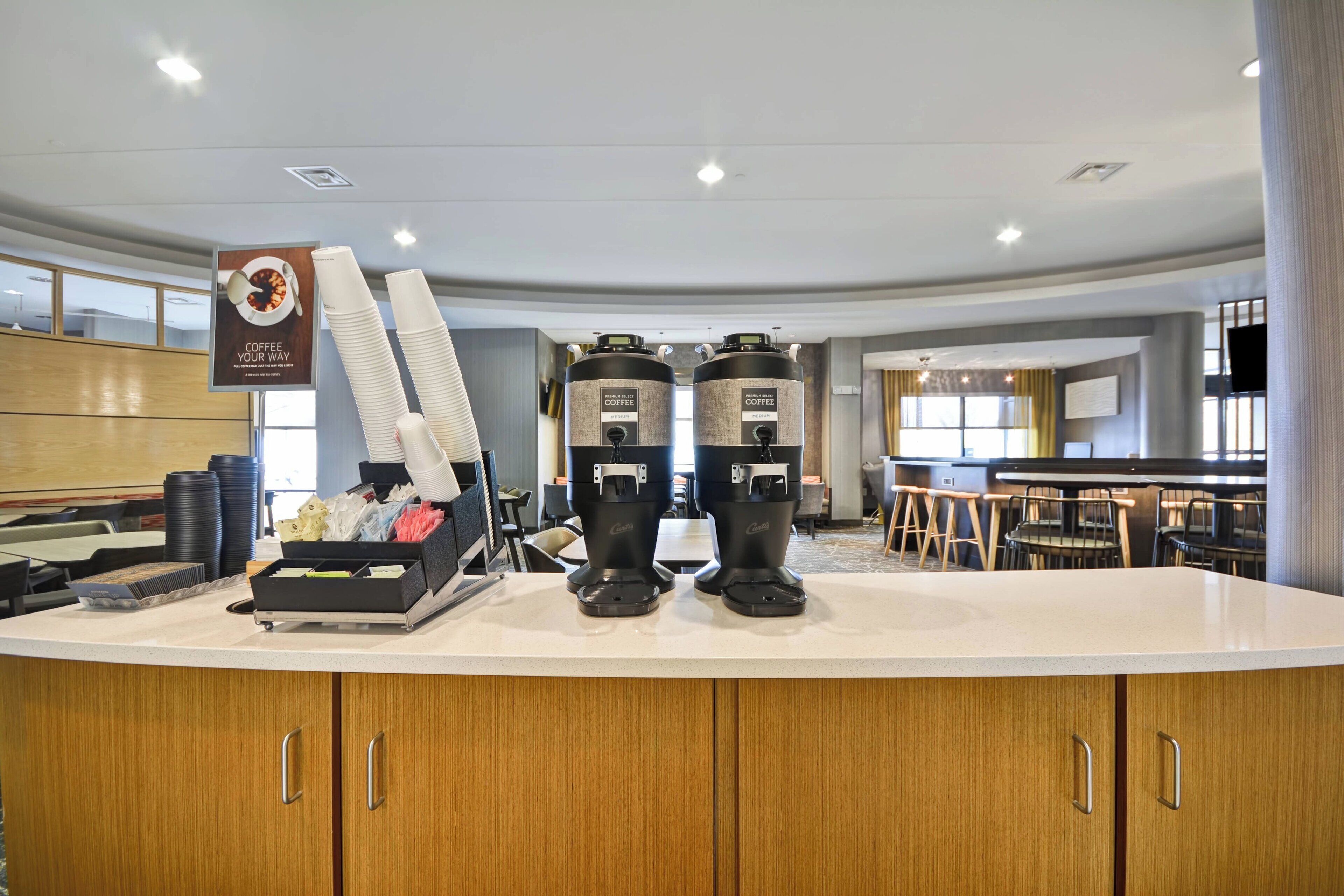 A coffee station with two coffee makers and a stack of disposable cups.