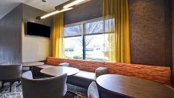 Une chambre d’hôtel moderne dotée d’une grande fenêtre, d’un téléviseur à écran plat et d’un coin salon avec des canapés et des tables.