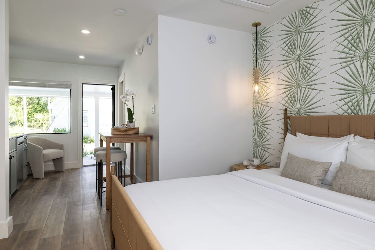Une chambre avec un grand lit, un bureau avec une chaise et une vue sur l’extérieur.
