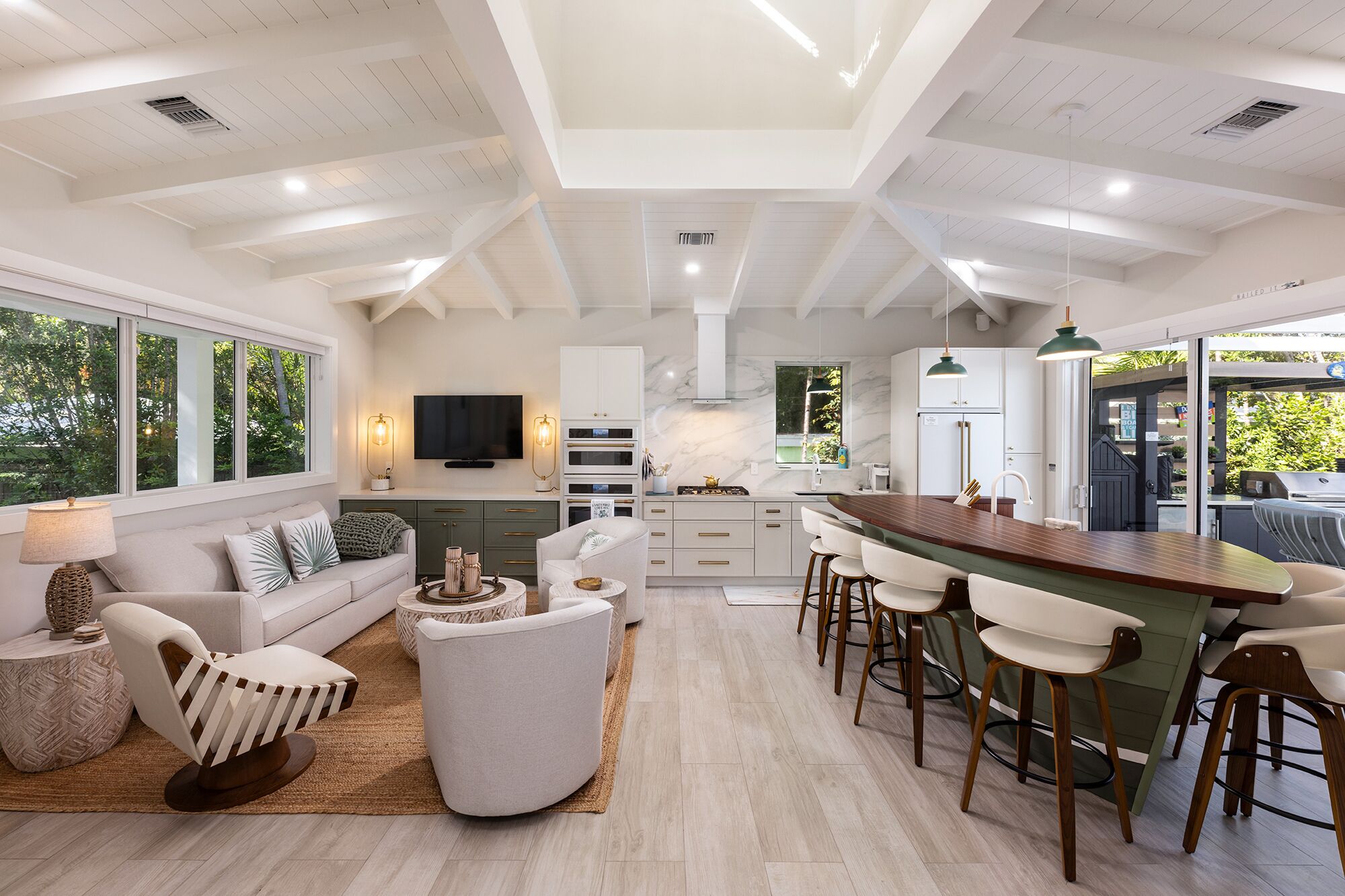 A modern kitchen with a bar area, built-in appliances, and a large window overlooking greenery.