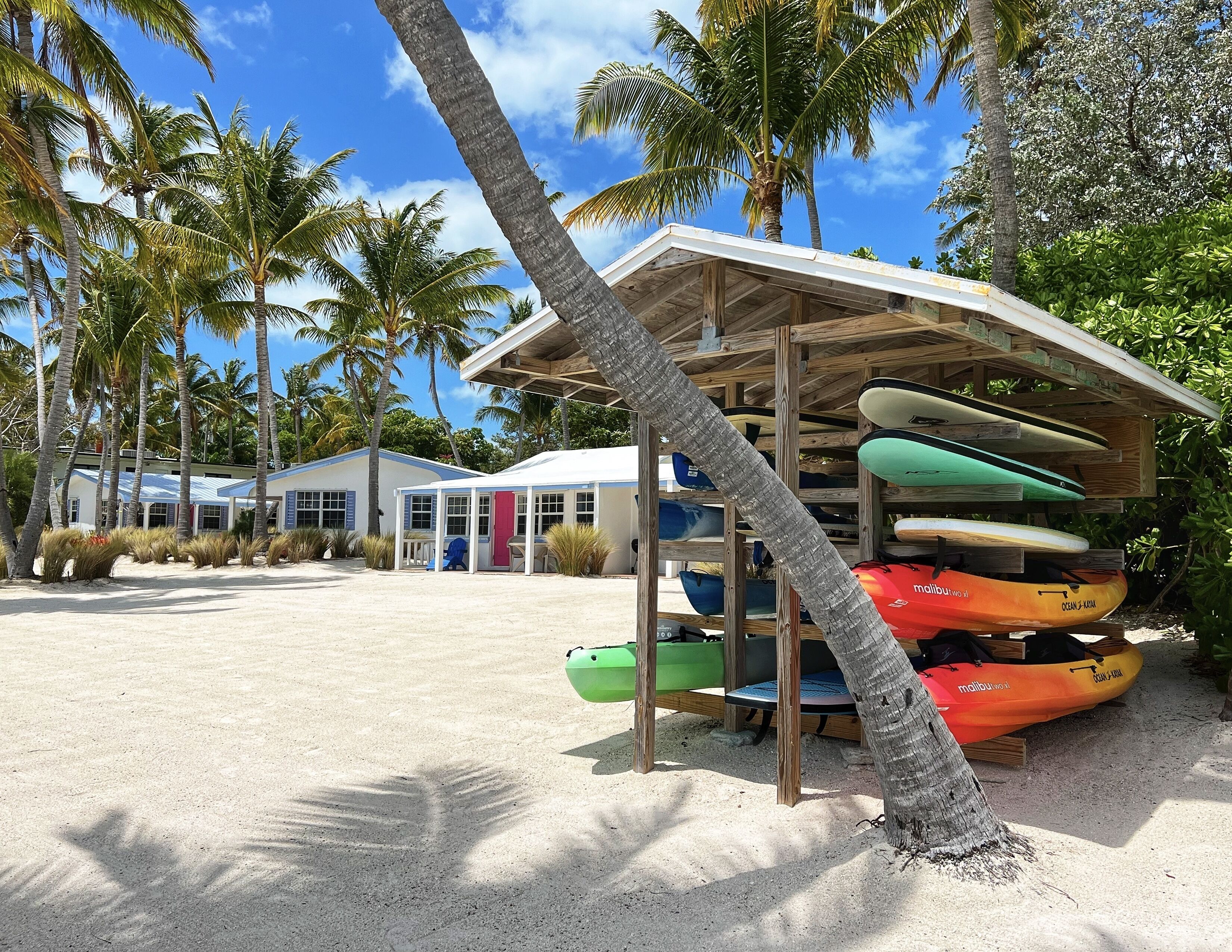 Un bâtiment situé au bord de la plage, doté d’un espace de repos couvert et d’une pile de kayaks.