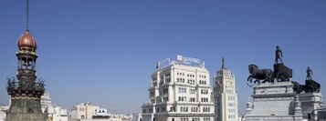 Stadtansicht mit einem markanten Gebäude, das eine Schautafel für Generali Versicherung trägt.