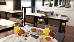 Un desayuno con platos de comida, incluyendo cruasanes, jamón y huevos, junto con vasos de jugo de naranja y un tazón de cereal.