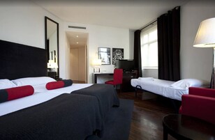Ein Hotelzimmer mit zwei Betten, einem Schreibtisch, einem Stuhl und einem Fernseher.