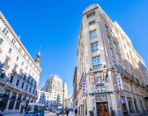 A hotel with a classic architectural style, featuring multiple floors, large windows, and a prominent entrance. - Hotel Quatro Puerta Del Sol (Madrid)