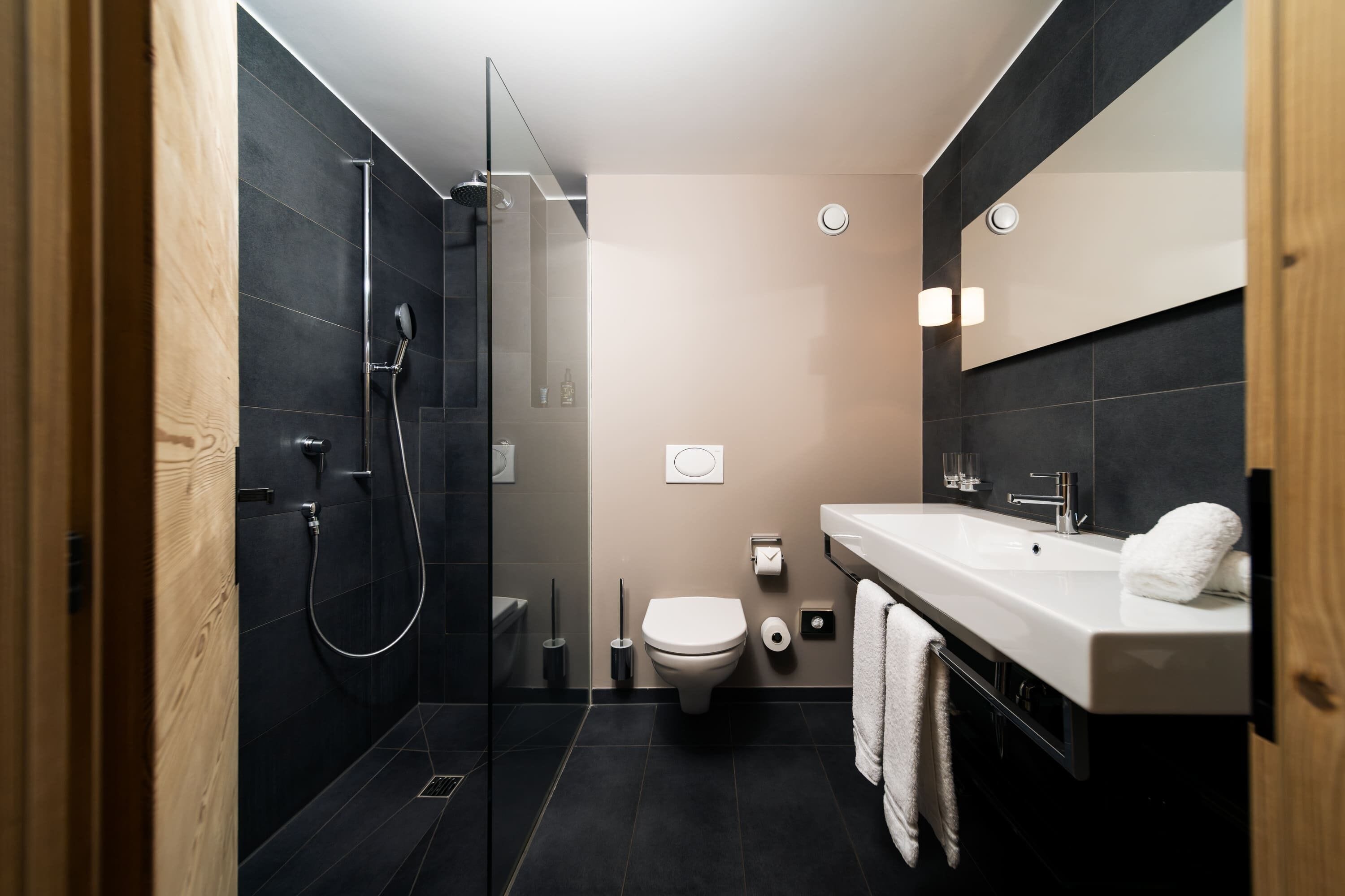 A modern bathroom with a glass-enclosed shower, a white toilet, and a sink with a towel.