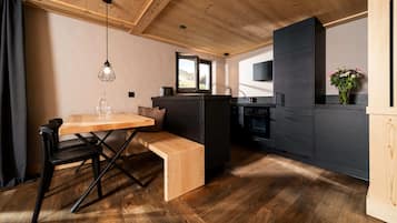 Una cocina moderna con techo de madera, zona de comedor con banco y una pequeña isla.