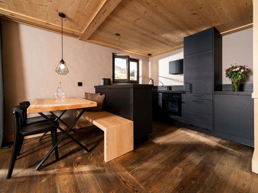 Una cocina moderna con techo de madera, zona de comedor con banco y una pequeña isla.