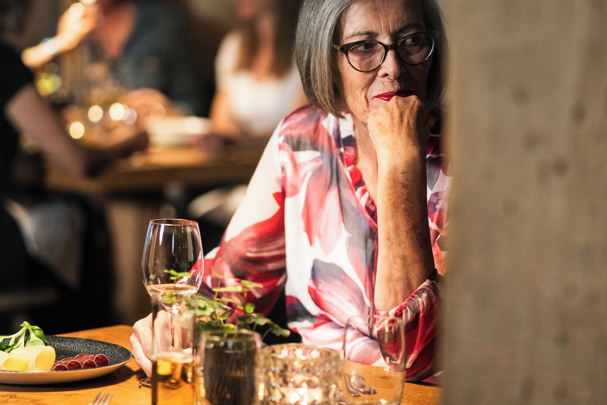 Una mesa de comedor con un plato de comida, una copa de vino y un vaso de agua.