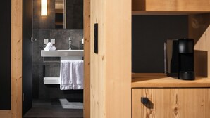 A modern bathroom with a wooden vanity, a sink, and a mirror. - Arc-en-Ciel Gstaad (Saanen)