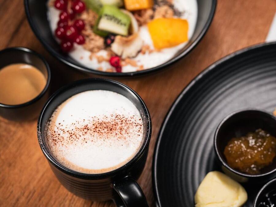 Ein Frühstückstisch mit einer Schüssel Müsli, einem Croissant und einer Tasse Kaffee.