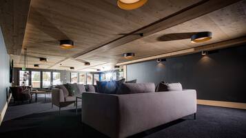 Un interno moderno con soffitto in legno, un divano grigio e un pavimento rivestito di moquette scura.
