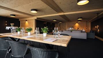 A spacious dining area with a long wooden table set for a meal, surrounded by wicker chairs.