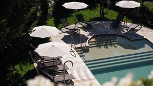 A poolside area with lounge chairs and umbrellas. - Arc-en-Ciel Gstaad (Saanen)