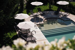 Un área junto a la piscina con sillones de descanso y sombrillas.