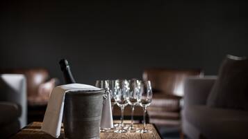 Une table en bois, sur laquelle se trouvent un seau en métal et une bouteille, entourée de verres à vin vides.