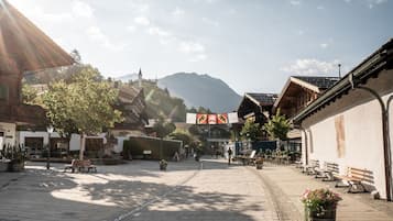 A cobblestone street in Gstaad with traditional buildings, benches, and a mountain in the background.