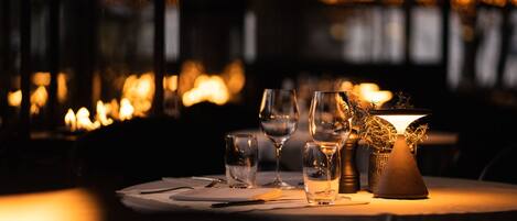 Un ambiente de restaurante con una mesa lista para comer, incluyendo copas de vino y un centro de mesa con velas.