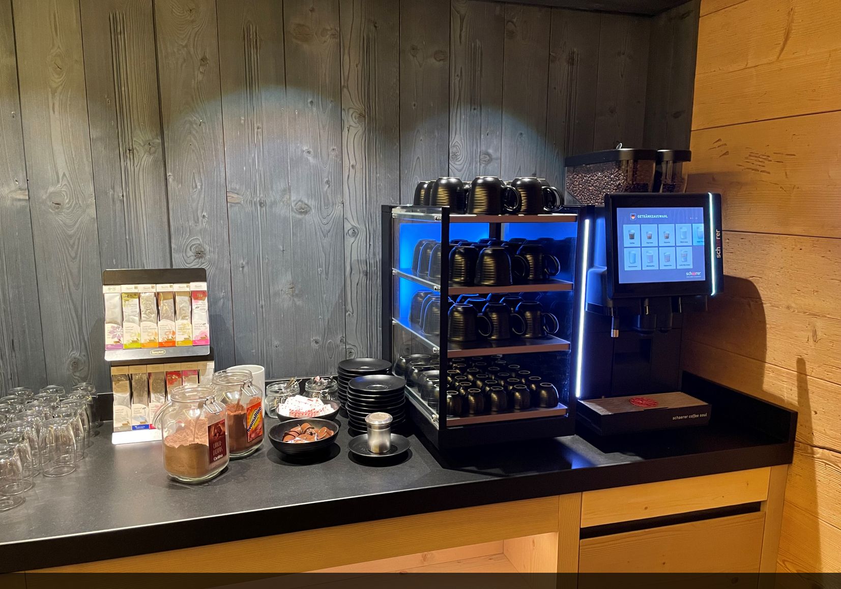Eine Kaffeestation mit Kaffeemaschine, Tassen und einer Auswahl an Kaffeekapseln.