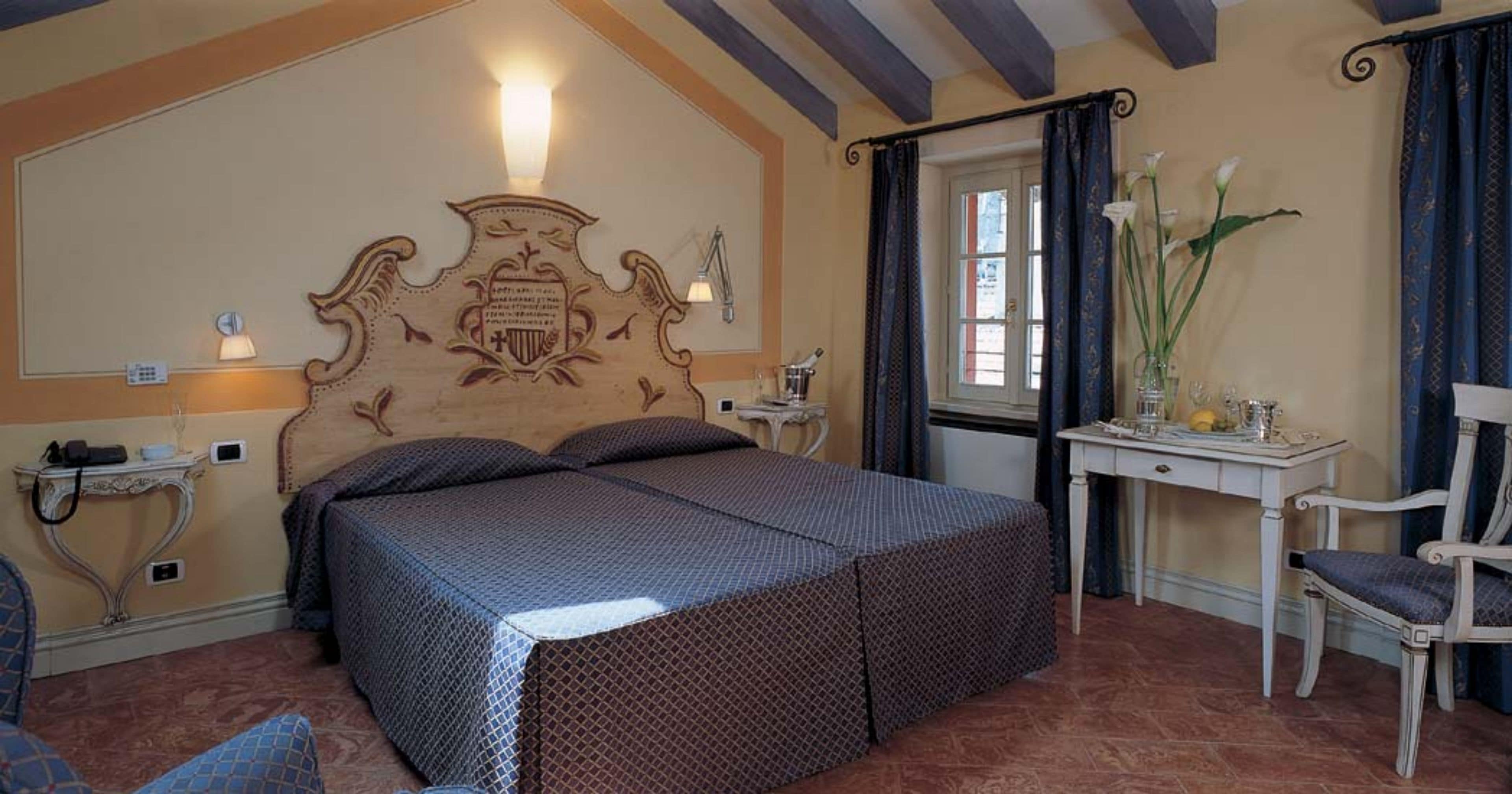 A bedroom with a large bed, a desk with a chair, and a window with curtains.