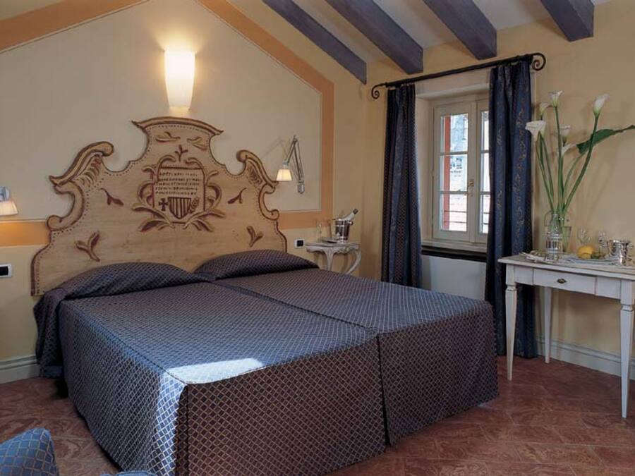 Un dormitorio con una cama grande, un escritorio con silla y una ventana con cortinas.