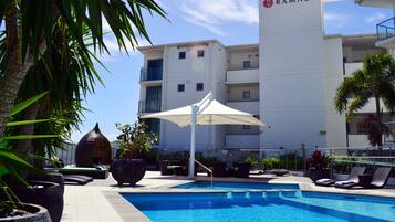 Una piscina al aire libre, sillones reclinables de piscina