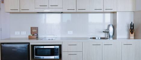A modern kitchen with light wood cabinets, a stainless steel microwave, and a dishwasher.