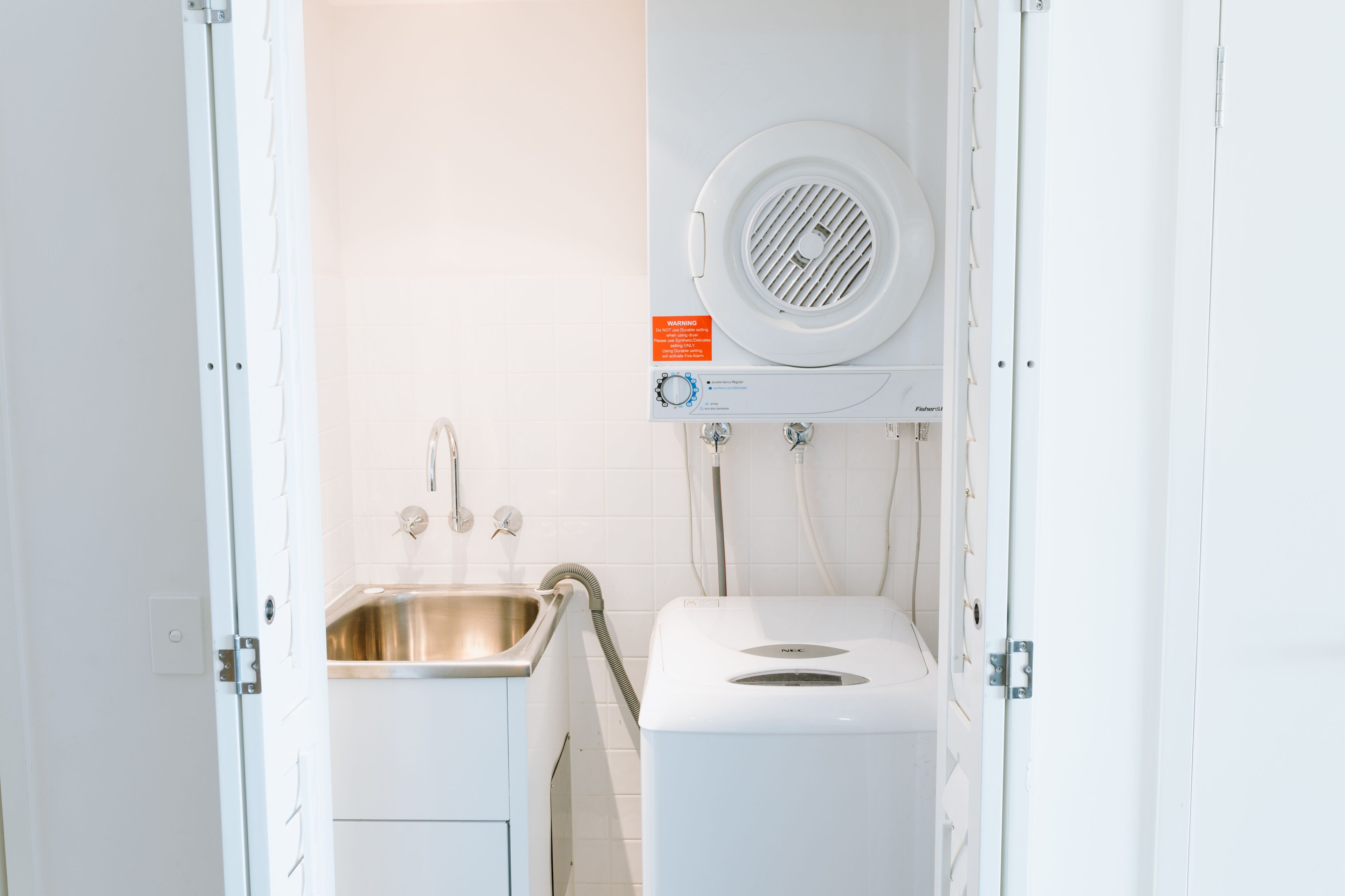 A compact bathroom with a sink, a toilet, and a built-in washing machine.