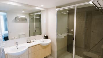 Un baño moderno con dos lavamanos, una cabina de ducha de vidrio y un espejo grande.