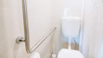 A bathroom with a handrail, a toilet, and a bidet.