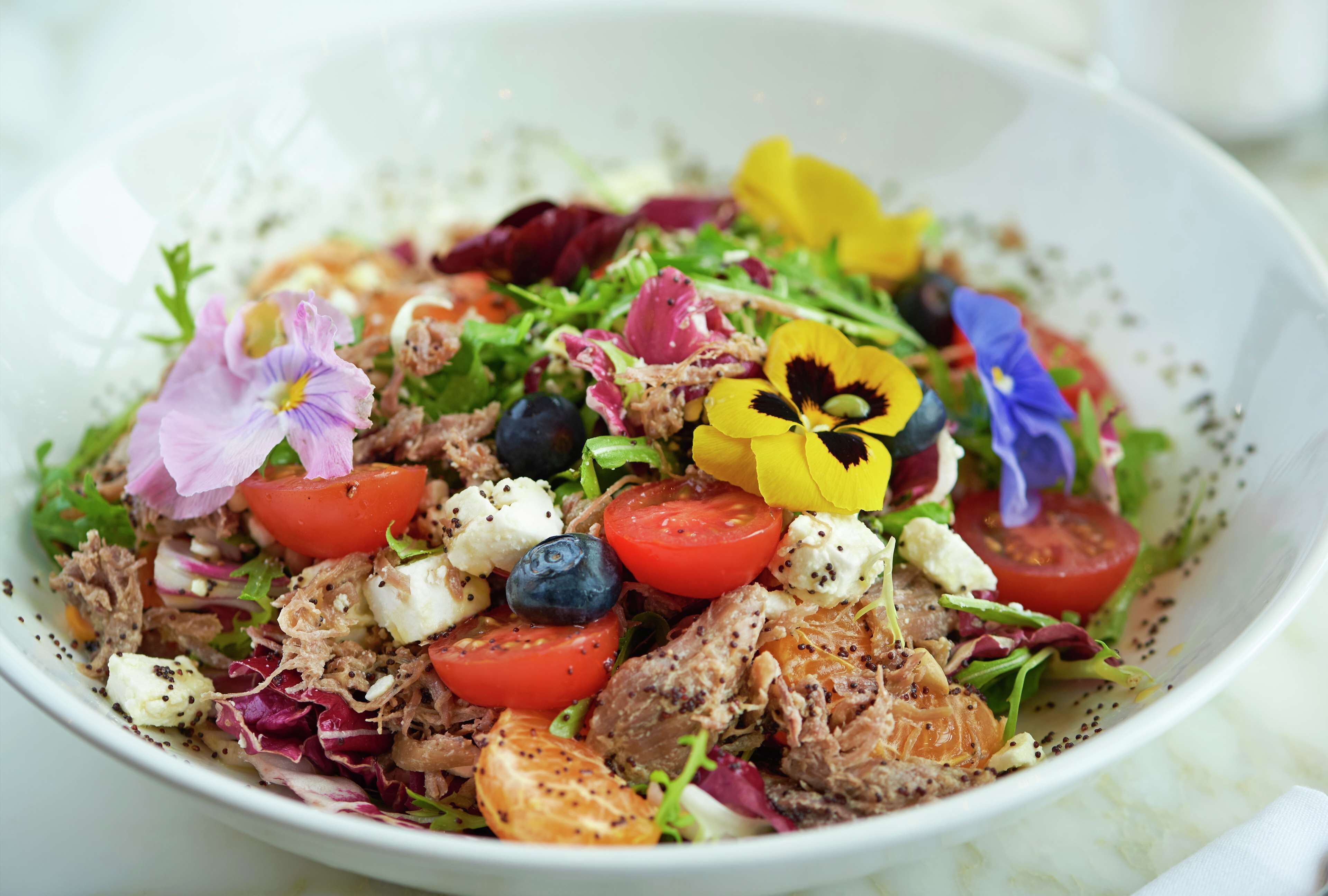 A bowl of salad with various vegetables and cheese.