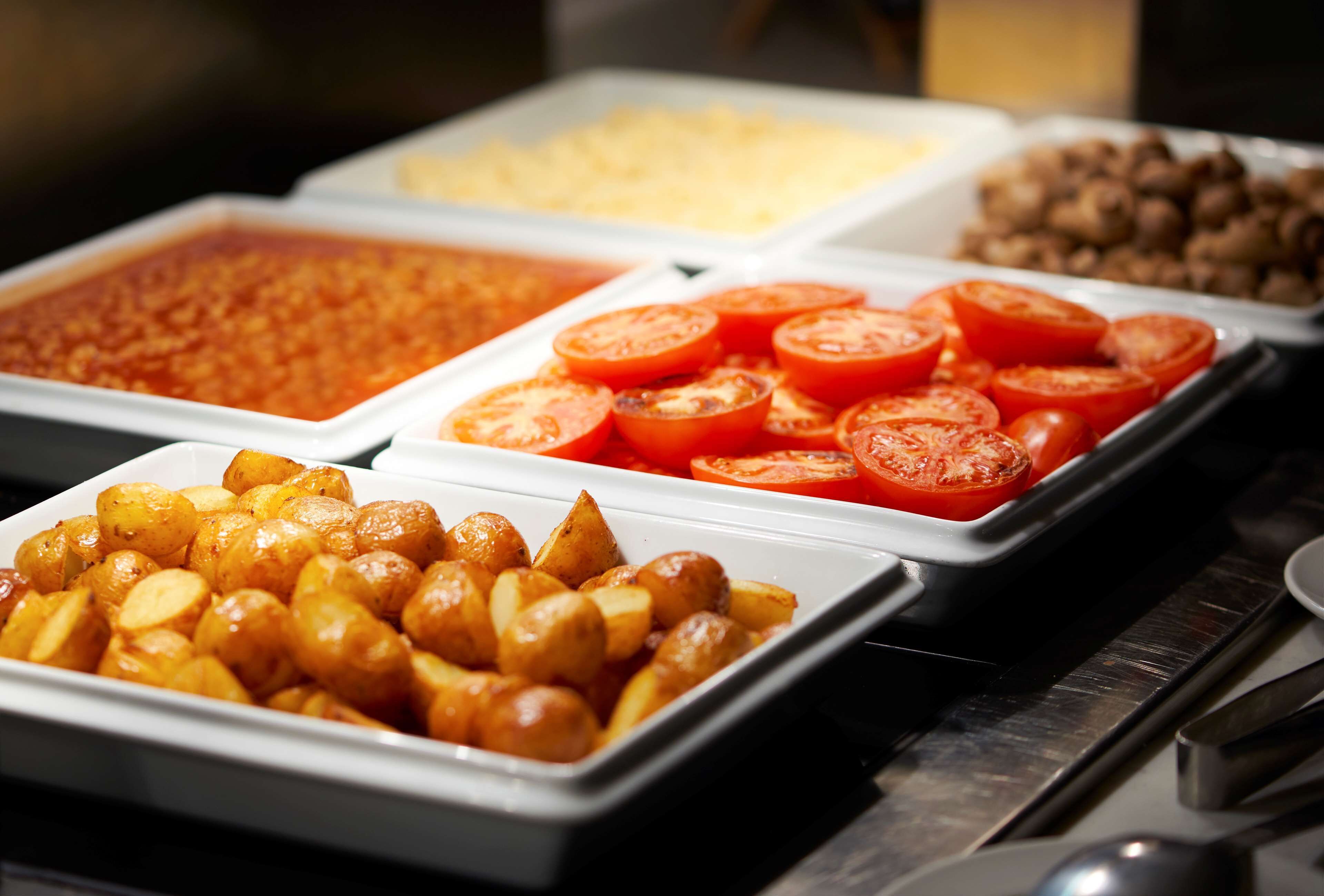 A buffet with various food items including roasted potatoes, sliced tomatoes, and other dishes.