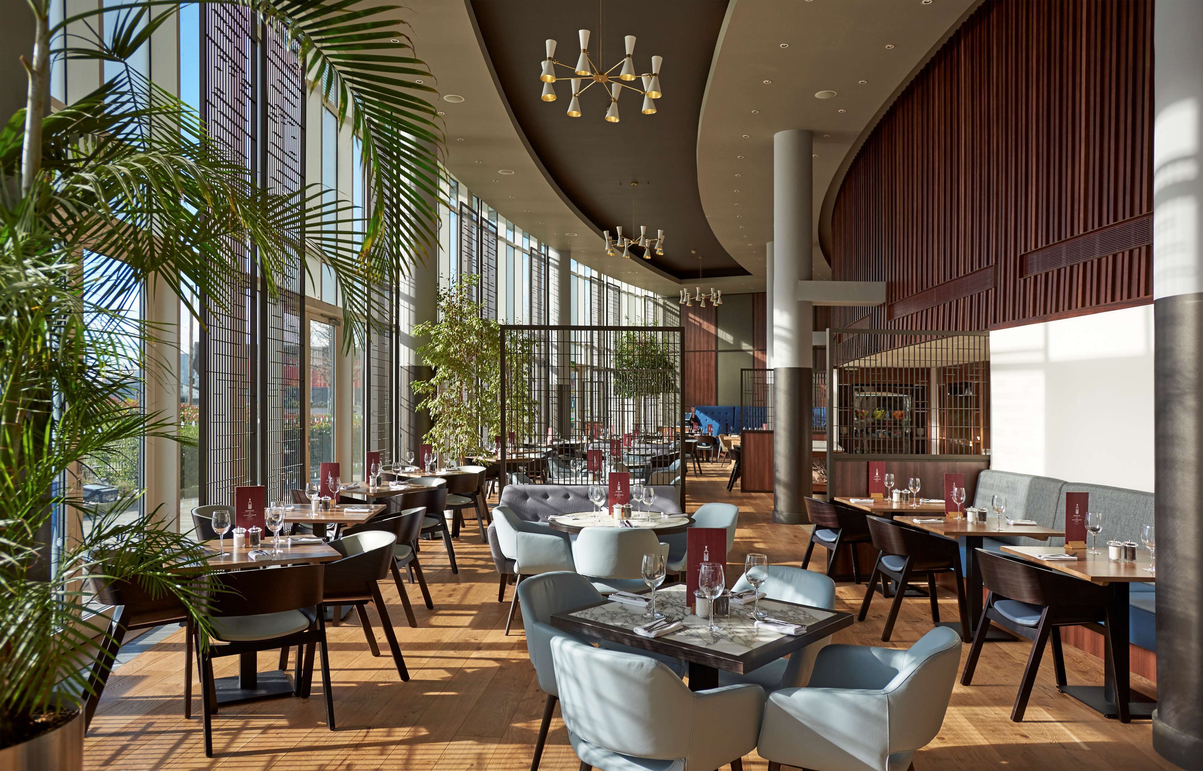Un restaurante espacioso con techos altos, ventanas amplias y luminarias modernas.