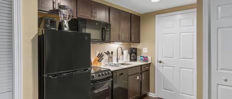 A kitchen with a refrigerator, stove, microwave, and oven. There is a sink and a countertop with various items.