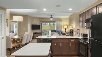 A modern kitchen with a refrigerator, stove, and microwave. There is a dining area with a table and chairs.