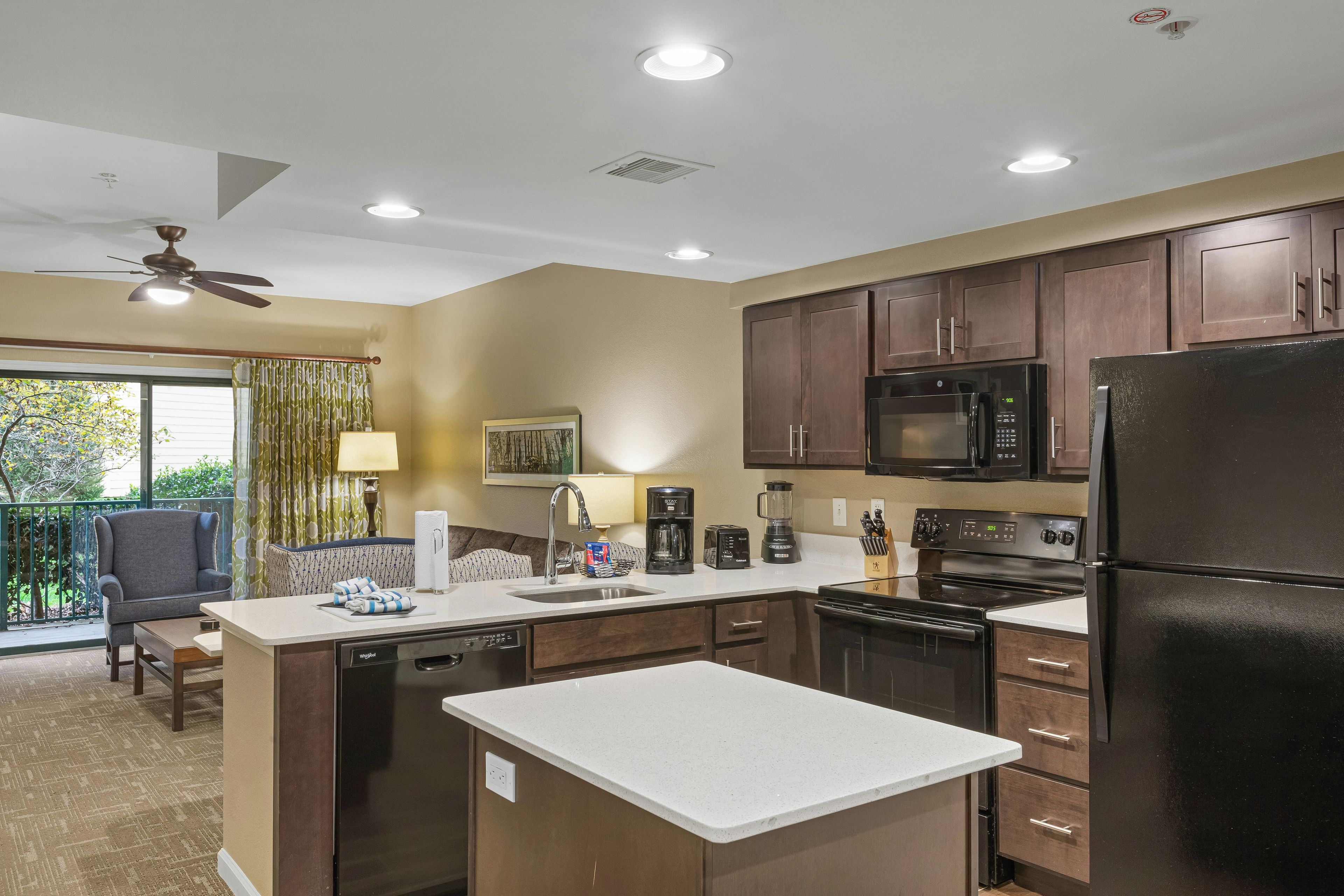 Una cocina moderna con armarios de madera oscura, un refrigerador negro y electrodomésticos de acero inoxidable.