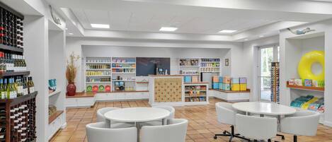 A modern interior with white walls, tiled flooring, and multiple white tables and chairs.