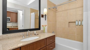 A bathroom with a sink, mirror, vanity, and bathtub.