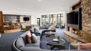 Een moderne woonkamer met een hoekbank, een bar en een stenen openhaard.