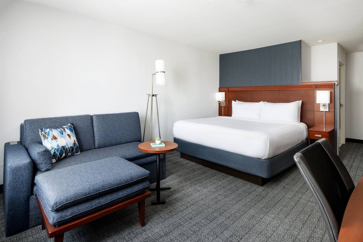Ein Hotelzimmer mit Bett, Sofa, kleinem Tisch und Lampe.