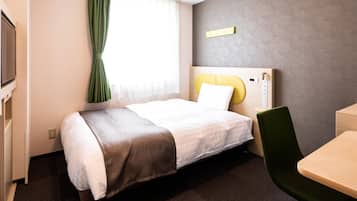 Une chambre d’hôtel avec un lit, un bureau, une chaise, une télévision et une fenêtre avec des rideaux.