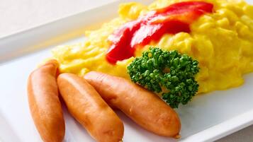 A plate with scrambled eggs, ketchup, sausages, and a broccoli floret.