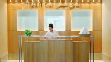 A reception desk with a wooden finish, a glass partition, and a sign above reading "HEALTH CLUB".