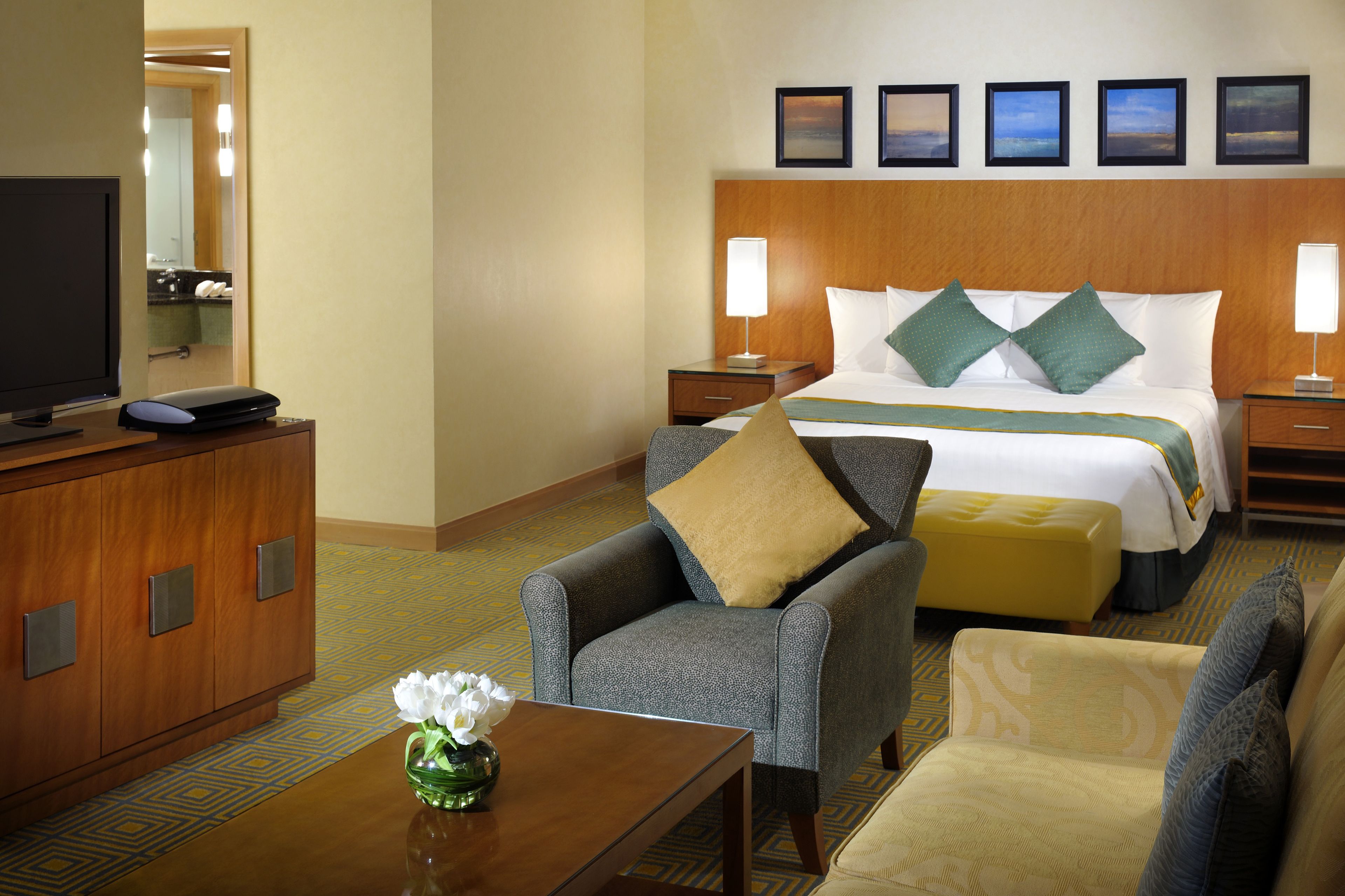 A hotel room with a bed, two bedside tables, a TV, a desk, and a chair.