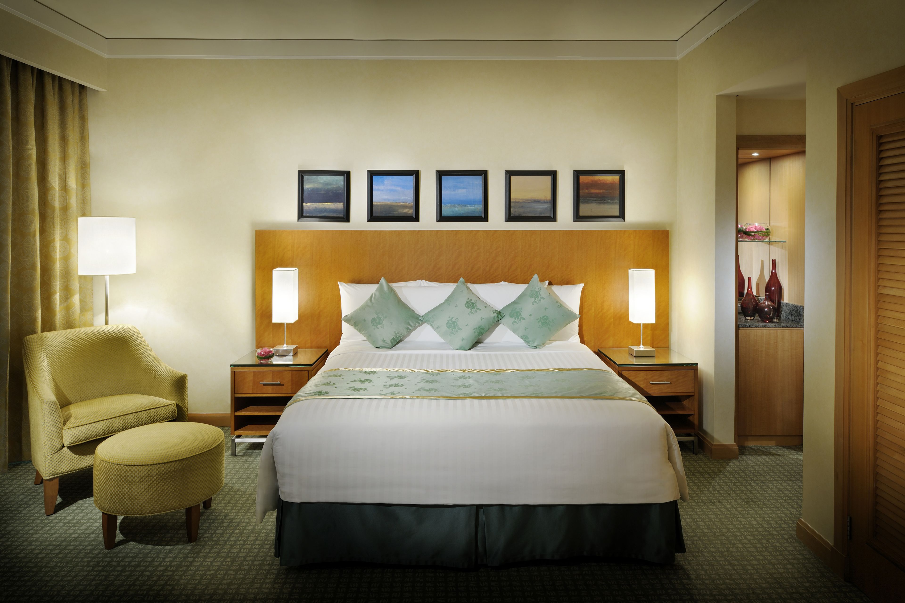 A hotel room with a large bed, two bedside tables, a chair, a lamp, and a view of the city.