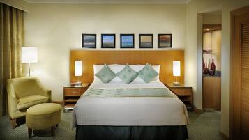 A hotel room with a large bed, two bedside tables, a chair, a lamp, and a view of the city.