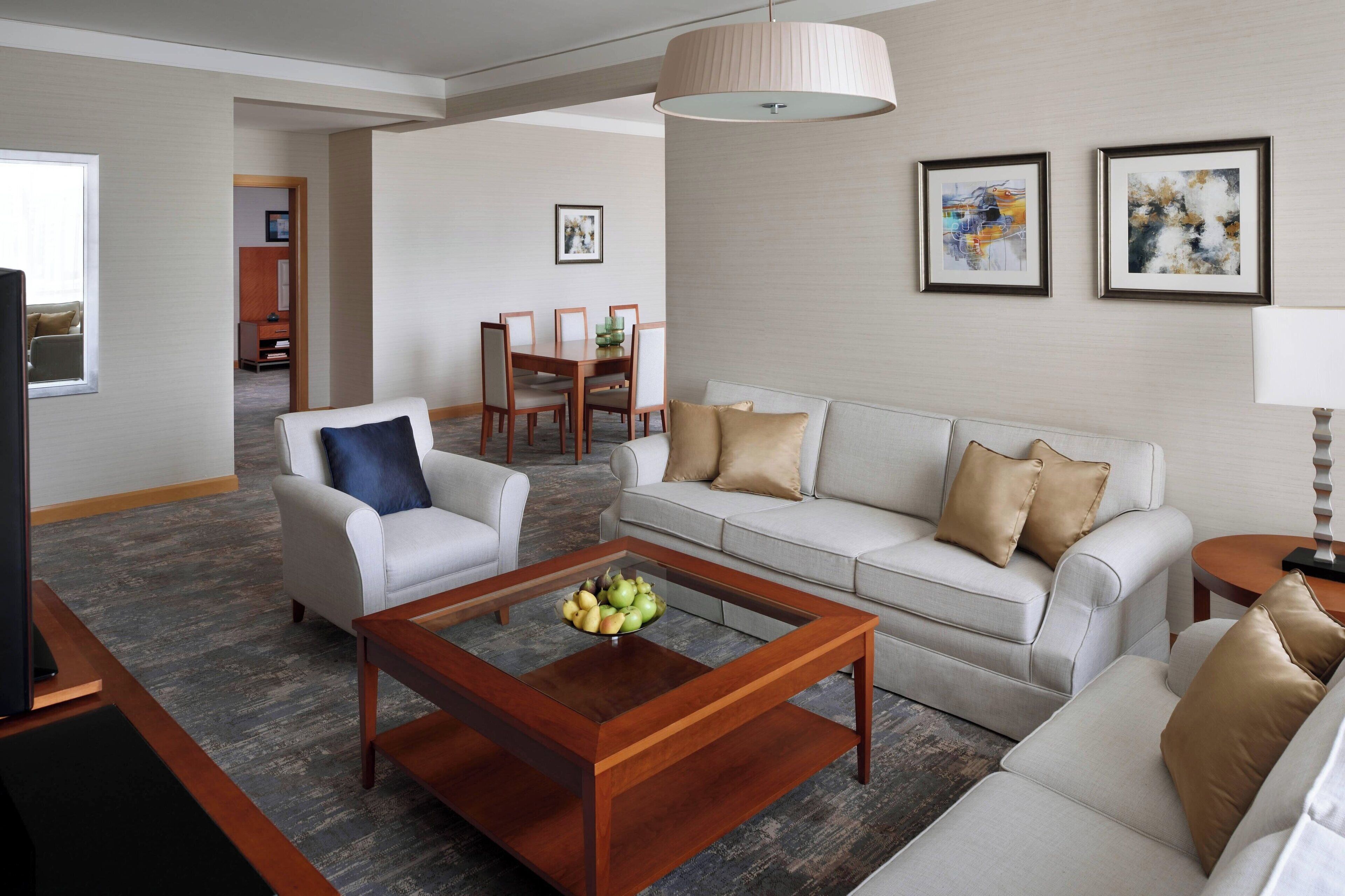 A modern living room with a sofa, armchair, coffee table, and dining area.