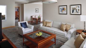 A modern living room with a sofa, armchair, coffee table, and dining area.