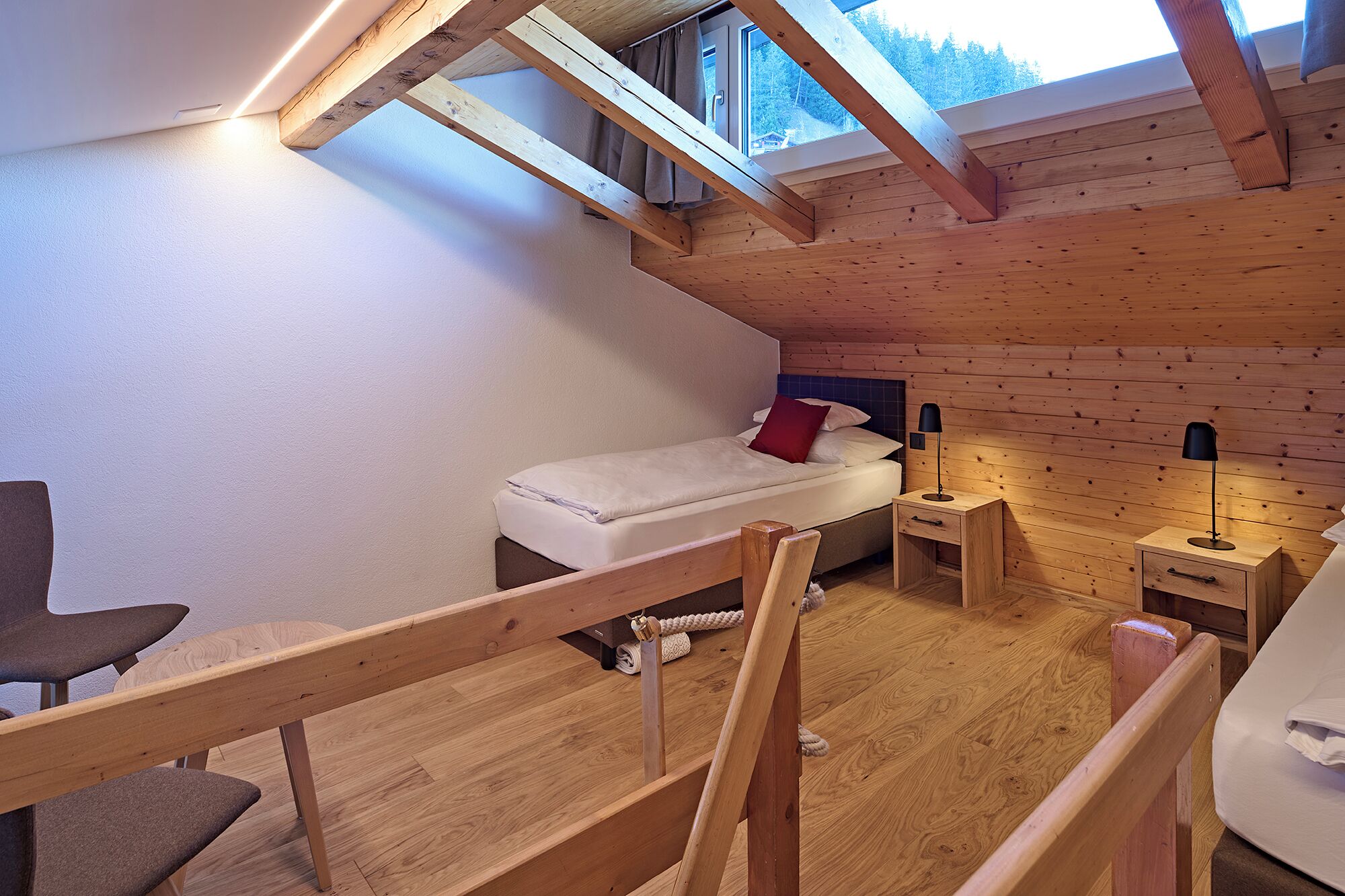 Une petite pièce agréable, dotée d’un lit en mezzanine, d’un bureau et d’une chaise.